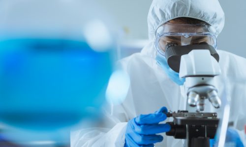 Young Asian handsome man scientist adjust focus and use Microscope to looking biochemical cell in laboratory. Doctor and scientist work in laboratory pandemic of corona virus, COVID19 concept